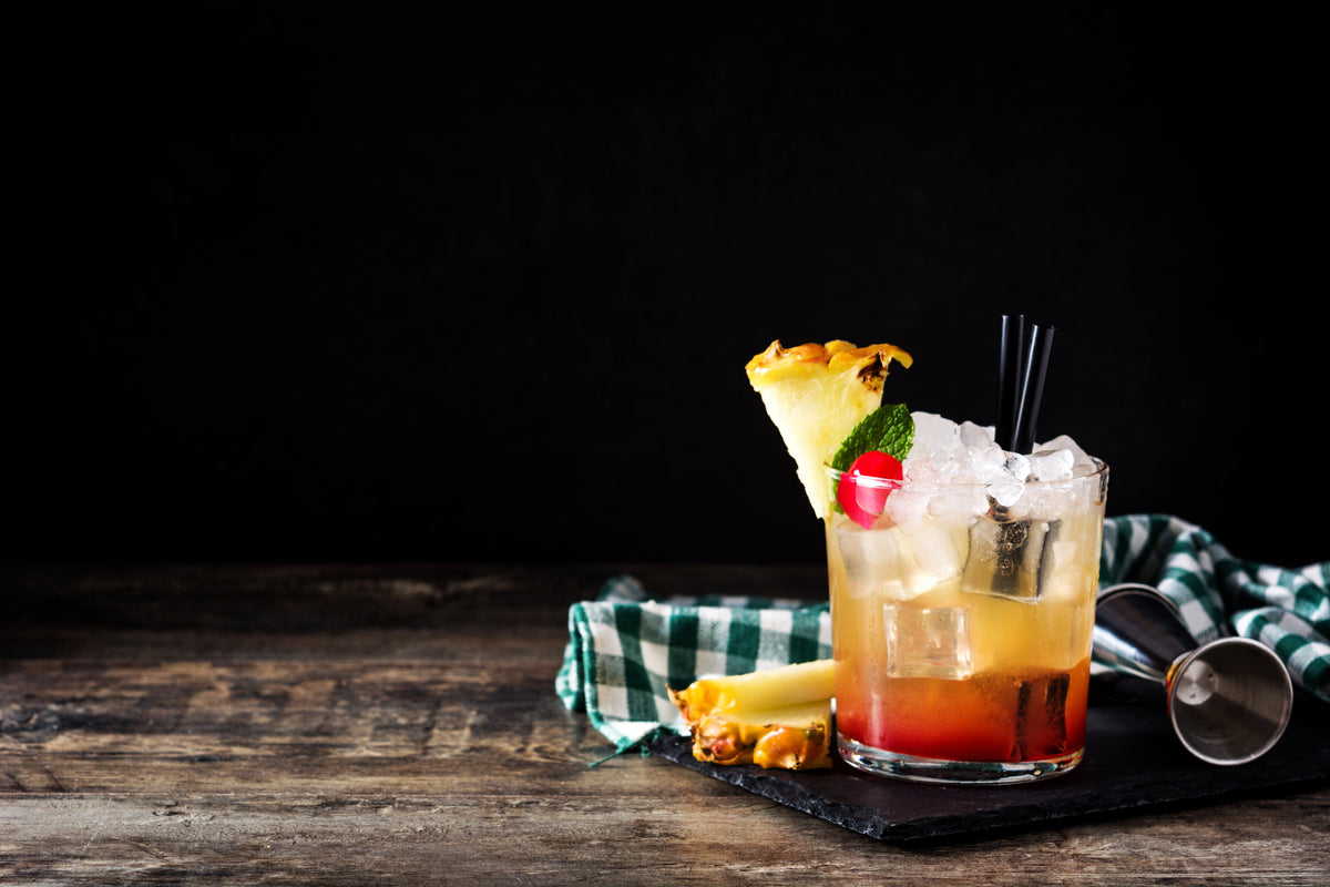 Cocktail with pineapple garnish on a dark background