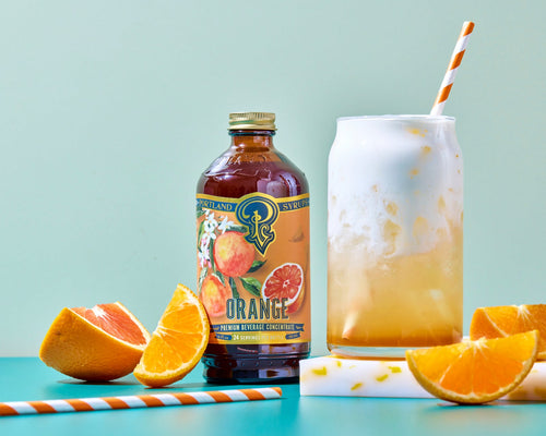Orange juice bottle with a glass of orange juice, oranges, and straws on a light blue background