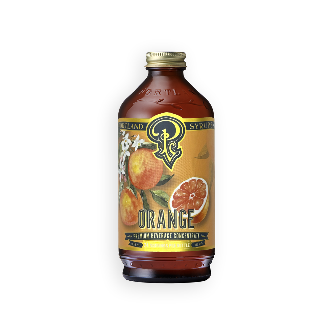 A bottle of Syrupland Premium Beverage Concentrate Orange flavor, featuring an amber glass bottle with a gold cap and a yellow-orange label decorated with illustrations of oranges and white blossoms.