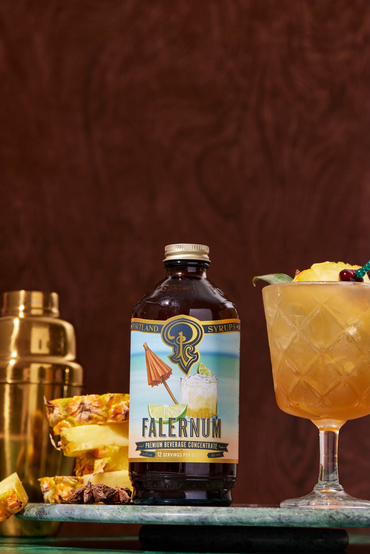 Bottle of Falernum with a cocktail and garnishes on a dark background