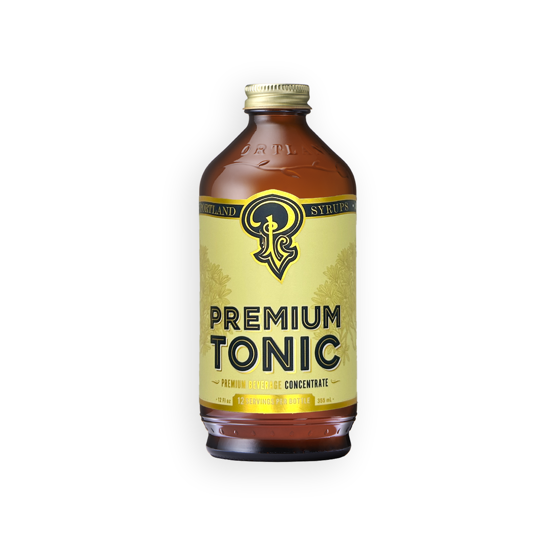 A bottle of Syrupsy Premium Tonic with an amber glass body, a gold cap, and a pale yellow label featuring a black logo and text, isolated on a white background.