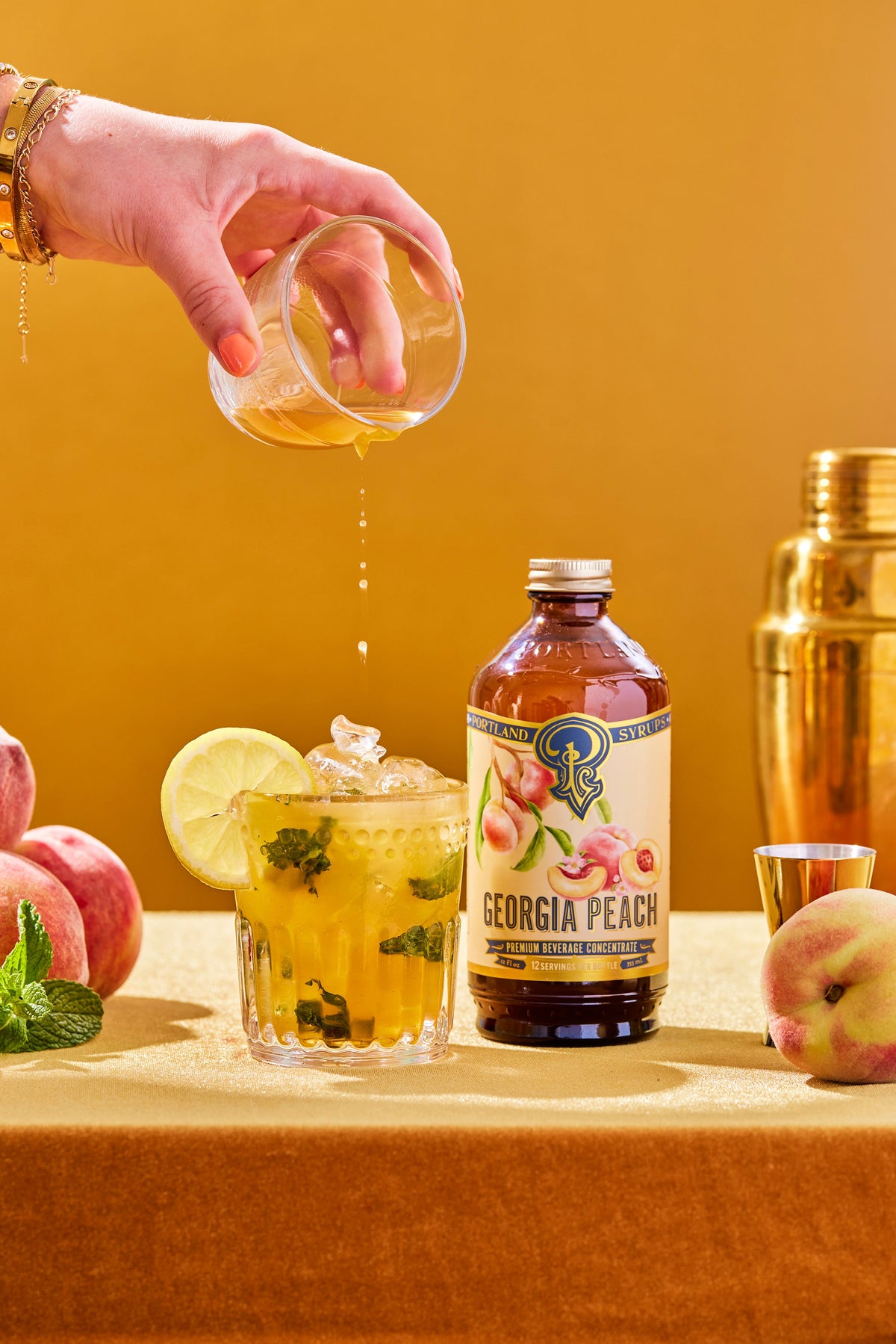 Georgia Peach bottle with a cocktail being poured and peaches on a table